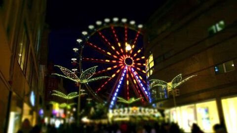 Sternschnuppenmarkt im Dunkeln, im Hintergrund ein beleuchtetes Riesenrad