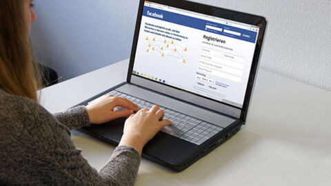 Mädchen sitzt am Laptop bei geöffneter Facebookseite