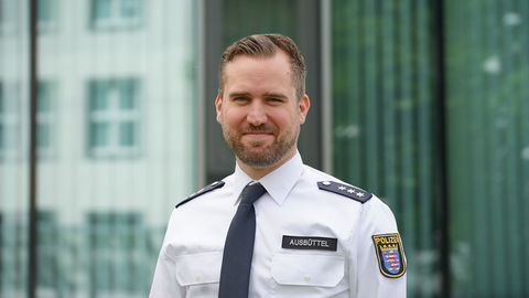 David Ausbüttel in weißer Uniform vor einem Gebäude