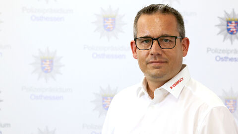 Ein Kollege in weißem Hemd vor der Medienwand mit dem Aufdruck Polizeipräsidium Osthessen