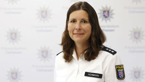 Eine Kollegin in weißem Uniformhemd vor der Medienwand mit dem Aufdruck Polizeipräsidium Osthessen