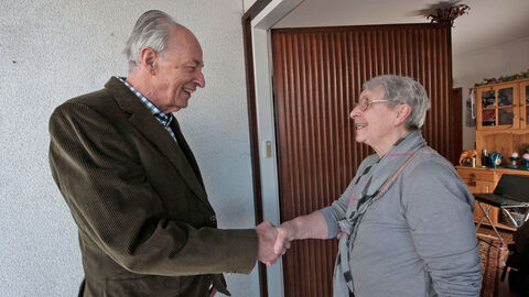 Wohnungstür: Älterer Mann gibt seiner älteren Nachbarin die Hand