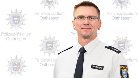 Ein Kollege in weißem Uniformhemd vor der Medienwand mit dem Aufdruck Polizeipräsidium Osthessen