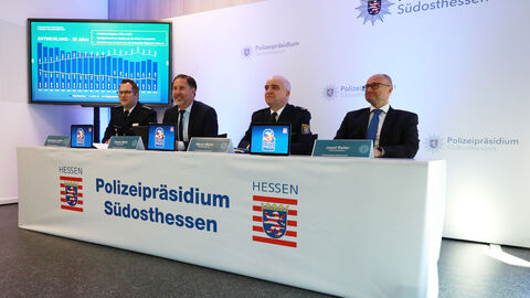 Christopher Leidner, Daniel Muth, Marco Weller und Josef Reiter sitzend neben einem TV-Monitor mit dargestellten Grafiken zur Kriminalstatistik 2024