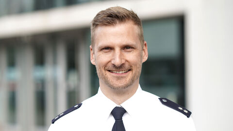 Fabian Dieckhoff in weißem Uniformhemd und Polizeipräsidium im Hintergrund