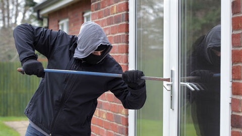 Person mit Brecheisen an Balkontür