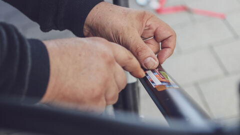 Hände bringen nach der Codierung einen Aufkleber auf dem Fahrradrahmen an