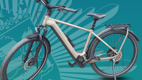 Ein weisses Fahrrad vor einer Wand mit einem Polizeistern in Grüntönen