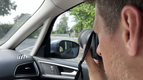 Eine Person fotografiert mit einer Kamera im Auto