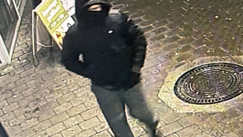 Foto des unbekannten Täters nach bewaffneten Raubüberfall auf Lebensmittelmarkt in Kassel-Waldau; Foto zeigt den Täter von schräg oben auf dem gehweg, bekleidet mit schwarzer Daunenjacke mit Kapuze, einer graue Hose und schwarzen Turnschuhe