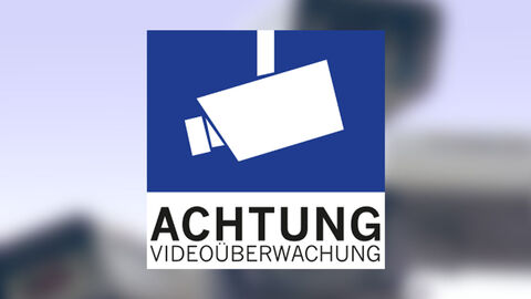 Achtung Videoüberwachung mit Kamerasymbol, im Hintergrund eine Viedeoüberwachungsanlage